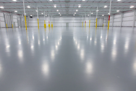Shiny, smooth epoxy-coated industrial floor in a large warehouse setting, showcasing a durable and professional finish
